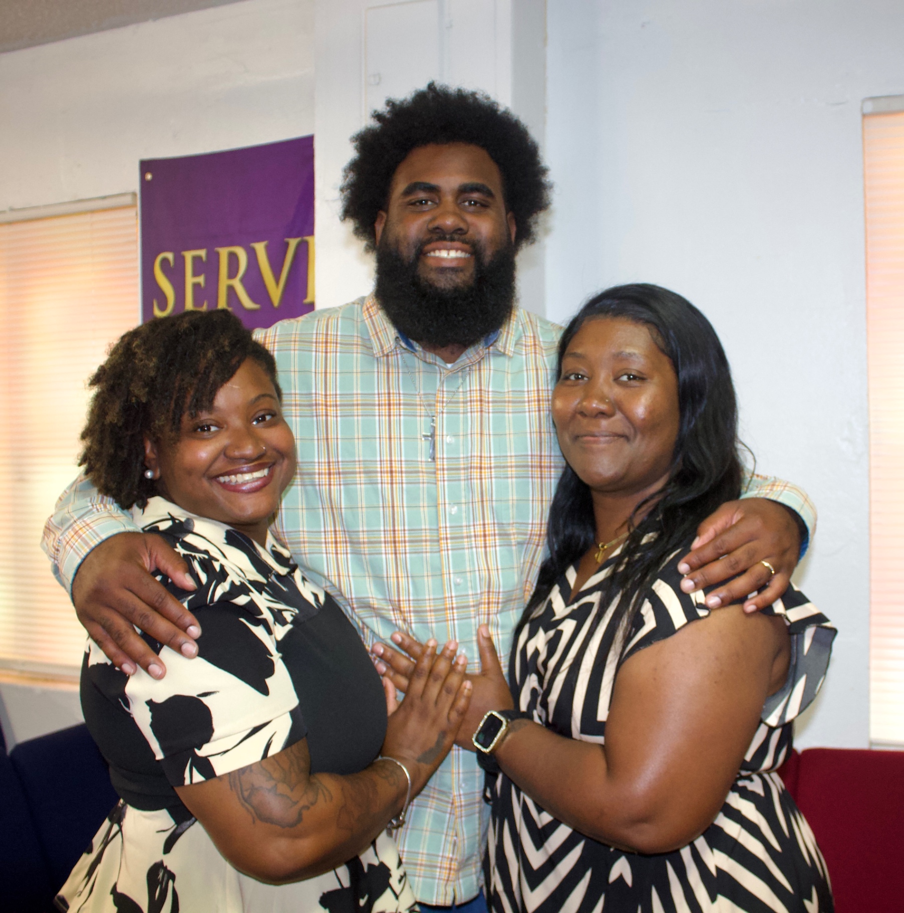 Three members of the church family smiling together in matching black and white outfits